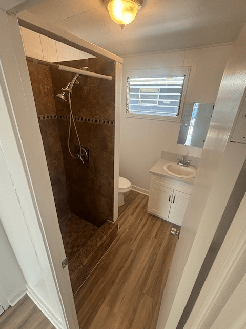 A small bathroom with a toilet, sink, and shower.